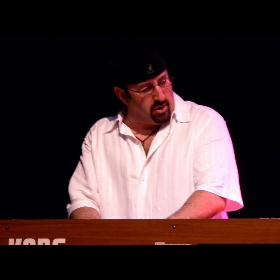 Jon Wolf playing keyboards live on a darkened stage